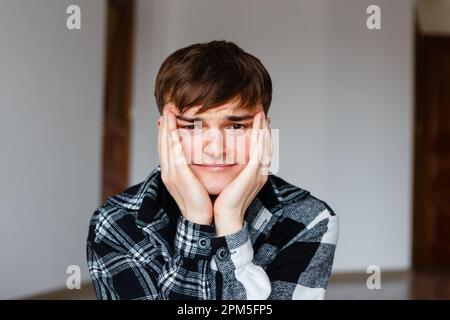 Der junge Mann hielt sich den Kopf fest und dachte über eine schwierige Entscheidung nach Stockfoto