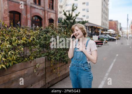 Eine glückliche Frau, die telefoniert und in die Stadt geht Stockfoto