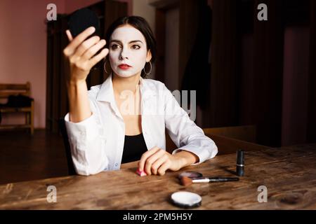 Die Schauspielerin schminkt ihr Gesicht, während sie im Probetheater sitzt Stockfoto