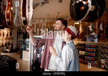 Ein junges Hipster-Paar, das nach einer neuen E-Gitarre für Auftritte sucht Stockfoto