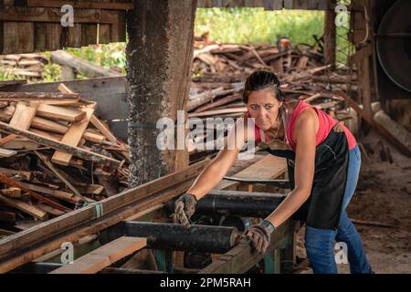 Porträt einer Frau, die mit besorgtem Gesicht zur Seite blickt und in einem Sägewerk arbeitet. Stockfoto
