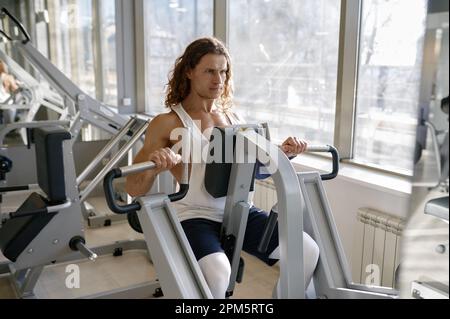 Portrait eines Sportlers, der hart trainiert und an einem Fitnessgerät trainiert Stockfoto