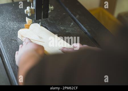 Zimmermann-POV. Unbekannte Holzbearbeitungsspezialistin, die Holz mit einer Holzfräsmaschine zu Herzen formt. Hochwertiges Foto Stockfoto