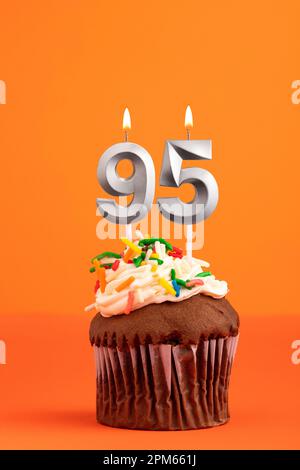 Kerze Nummer 95 - Kuchen zum Geburtstag auf orangefarbenem Hintergrund Stockfoto