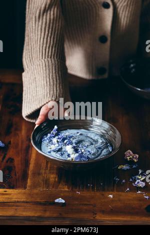 Superfood Smoothie Schüssel auf einem Holztisch gehalten in den Händen einer Frau Stockfoto