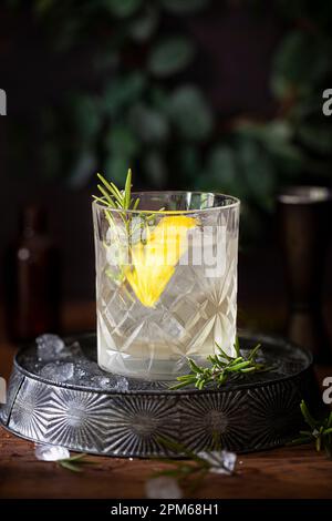 Ein weißer negroni-Gin-Cocktail mit Zitronen- und Rosmarin-Garnierungen. Stockfoto