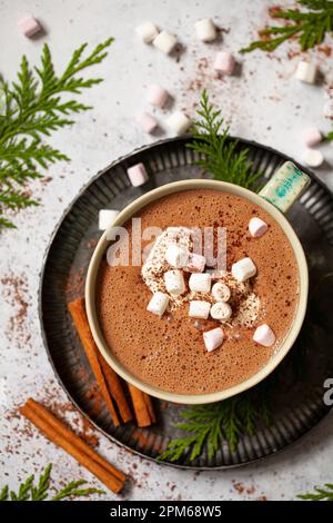Blick von oben auf heiße Schokolade in einem blau-grünen Becher mit Schlagsahne und Mini-Marshmallows. Stockfoto