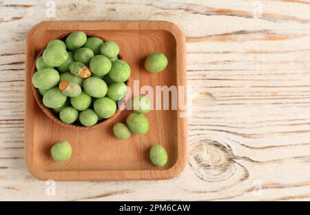 Leckere Wasabi-beschichtete Erdnüsse auf einem weißen Holztisch, Blick von oben. Platz für Text Stockfoto