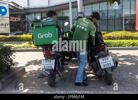 SAMUT PRAKAN, THAILAND, JANUAR 21 2023, Motorradfahrer des Grab Lieferservice, im Schatten auf dem Bürgersteig geparkt Stockfoto