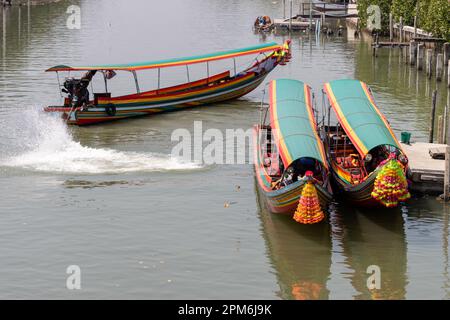 Traditionelle hölzerne Boote mit Blumen auf der Nase sind am Anleger in Thailand verankert Stockfoto