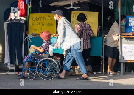 SAMUT PRAKAN, THAILAND, APR 07 2023, Ein Mann schiebt einen Rollstuhl mit einer alten Frau auf dem Markt Stockfoto