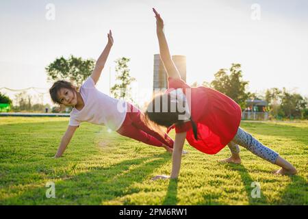 Kindermeditation mit Yoga-Pose auf grünem Grasfeld. Aktivitäten im Freien für Kinder, Yoga-Übungen, Kinder können lernen, wie man trainiert. Stockfoto