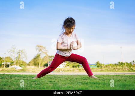 Kindermeditation mit Yoga-Pose auf grünem Grasfeld. Aktivitäten im Freien für Kinder, Yoga-Übungen, Kinder können lernen, wie man trainiert. Stockfoto