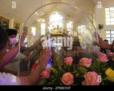 Navotas, Philippinen. 11. April 2023. Katholische Gläubige berühren und reiben ihre Taschentücher mit St. Theresisches Bild an der Glaseinhausung der Relikte von St. Therese von Lisieux. Die Relikte von St. Therese des Kindes Jesus, auch bekannt als Therese von Lisieux, erreichte die Diözese von Kalookan, die die Städte Malabon, Navotas und den südlichen Teil von Caloocan umfasst. Der erste Halt war in San Lorenzo Ruiz & Companion Martyrs Parish in Navotas City. Es ist der 5. Pilgerbesuch der Reliquie im Land. Kredit: SOPA Images Limited/Alamy Live News Stockfoto