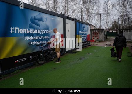 Borodyanka, Ukraine. 6. April 2023. Einwohner, die am temporären Wohnmobil vorbeikommen. Trotz der einjährigen Befreiung von Borodyanka, einer Stadt nordwestlich der ukrainischen Hauptstadt Kiew, sind die Bewohner von Borodyanka nicht zur Normalität zurückgekehrt. Der Wiederaufbauprozess verlief stetig, aber langsam, zerstörte Gebäude bleiben im Stadtzentrum. Viele Bewohner leben in beschädigten Gebäuden, die jetzt teilweise repariert sind, während andere, die ihr Zuhause verloren haben, immer noch in provisorischen Wohnungen leben. Die Beamten sind sich noch nicht sicher, wann diese Menschen nach Hause zurückkehren können. Borodyanka war es Stockfoto