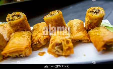 Federrolle, in Abschnitte geschnitten und künstlerisch auf einer langen weißen Platte verteilt. Stockfoto