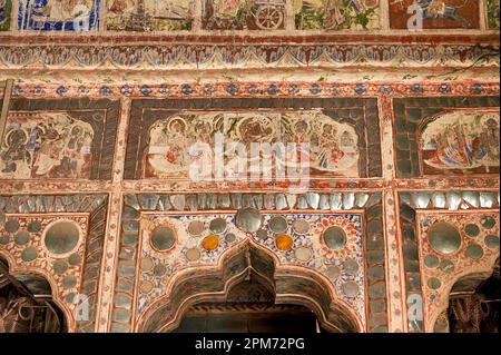 Farbenfrohe mythologische Gemälde und Spiegelarbeiten an der Decke eines kleinen Shani Mandir in Ramgarh, Shekhawati, Rajasthan, Indien Stockfoto