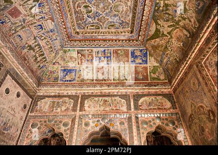 Farbenfrohe mythologische Gemälde und Spiegelarbeiten an der Decke eines kleinen Shani Mandir in Ramgarh, Shekhawati, Rajasthan, Indien Stockfoto