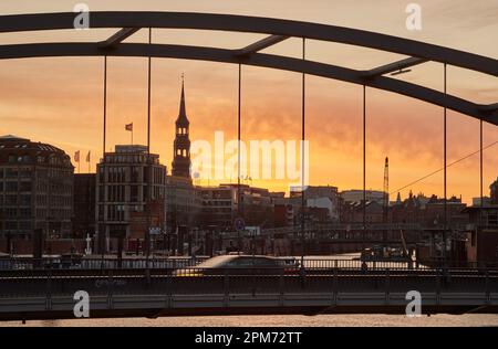 Hamburg, Deutschland. 12. April 2023. Kurz vor Sonnenaufgang leuchtet der Himmel an der Niederbaumbrücke Ost über dem Binnenhafen rot. Laut Wetterdienst wird es in den nächsten Tagen instabil bleiben. Kredit: Georg Wendt/dpa/Alamy Live News Stockfoto