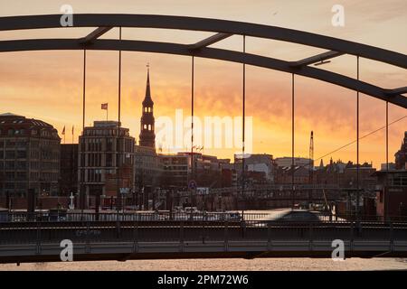 Hamburg, Deutschland. 12. April 2023. Kurz vor Sonnenaufgang leuchtet der Himmel an der Niederbaumbrücke Ost über dem Binnenhafen rot. Laut Wetterdienst wird es in den nächsten Tagen instabil bleiben. Kredit: Georg Wendt/dpa/Alamy Live News Stockfoto