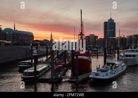 Hamburg, Deutschland. 12. April 2023. Kurz vor Sonnenaufgang leuchtet der Himmel über dem Hafen von Niederhafen rot. Laut Wetterdienst wird es die nächsten Tage instabil bleiben. Kredit: Georg Wendt/dpa/Alamy Live News Stockfoto