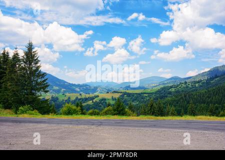 Die Straße führt durch die friedliche Landschaft und bietet Reisenden einen malerischen Pfad. Die ruhige Landschaft wird nur durch die majestätischen Berge auf t unterbrochen Stockfoto