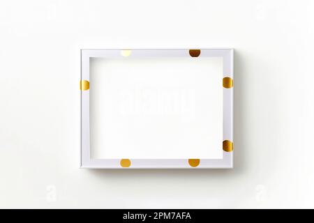 Weißes Rahmenmodell an weißer Wand mit goldenen Punkten. Minimalismus Stockfoto