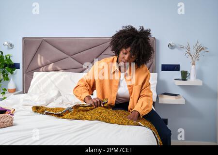 Eine Afrikanerin faltete einen Schal, um zu Hause eine Frisur daraus zu machen. Stockfoto