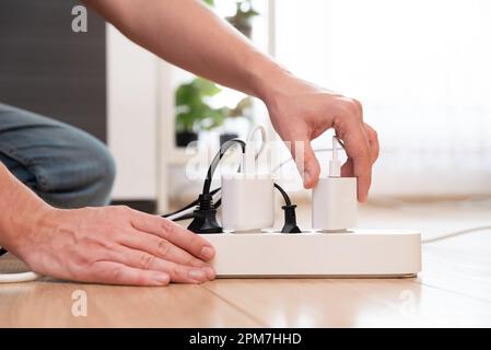 Handgehaltener Elektrostecker, Mehrfachsteckdose mit angeschlossenen Steckern, Energieeffizienz Stockfoto