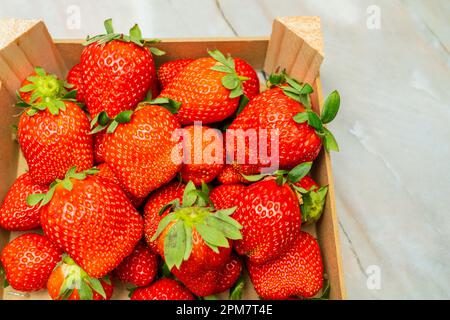 Eine Holzkiste voller frisch gepflückter, reifer roter Erdbeeren. Stockfoto