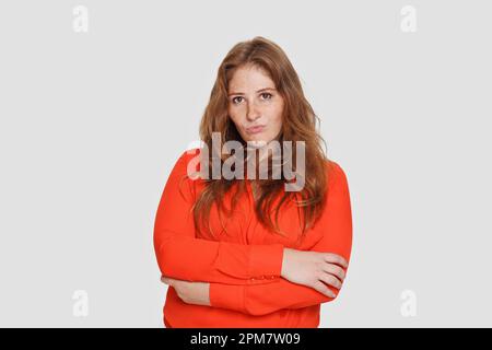Porträt einer rothaarigen Frau, die ein rotes Hemd auf weißem Hintergrund trägt Stockfoto