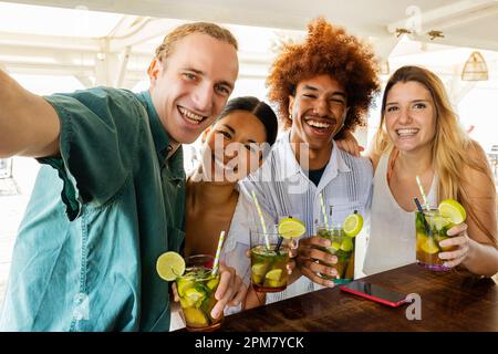 Fröhliche junge Gruppe von Freunden, die Selfie machen, während sie Mojito am Strand genießen Stockfoto