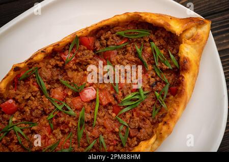 Köstlicher Pide gefüllt mit gewürztem Fleisch auf Holzhintergrund Stockfoto