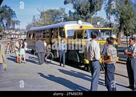 Der Bahnhof in Cochabamba, Bolivien, 1968. Am Bahnsteig steht ein Eisenbahnbus. Angepasste Motorbusse und Minibusse, die von Unternehmen wie Dodge und Mercedes hergestellt wurden, wurden umgebaut, um auf ländlichen Bahnstrecken im Land zu fahren – sie wurden als Ferro Carril, Ferrovia Andina Ferrobus und Bus Carril bezeichnet und von der Eisenbahngesellschaft FCA (Empresa Ferroviaria Andina) betrieben. Der Eisenbahnbus 272 ist ungewöhnlich, wenn er von einem separaten, knickgelenkten Lkw-Fahrerhaus mitgezogen wird. Cochabamba (oder Quchapampa, Quechua oder Quchapampa) ist die größte Stadt zwischen La Paz und Santa Cruz de la Sierra – ein altes 1960er-Foto. Stockfoto