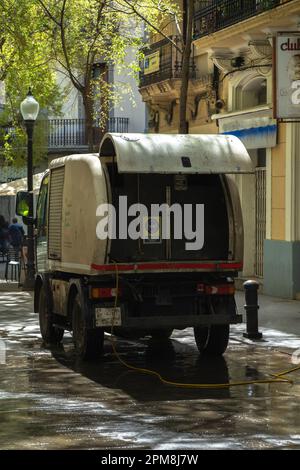 Hinter einem Putzwagen von der städtischen Brigade von Barcelona, säuberte eine Fußgängerzone mit dem Schlauch, der die ganze Straße bewässerte. Stockfoto