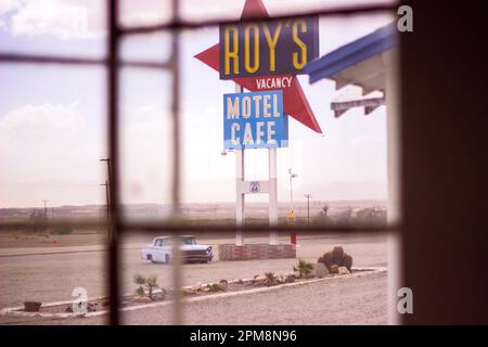 Dieses gespenstische Foto zeigt die trostlose Schönheit eines verlassenen Motelzimmers in Amboy, Kalifornien, mit dem ikonischen Schild von Roy's Motel und einem sichtbaren Auto Stockfoto