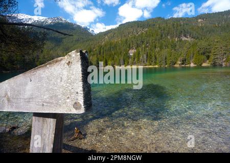 Tiroler Landschaft intakte Landschaft am idyllischen klaren Bergsee mit Holzzaun, teilweise bewölkter blauer Himmel, schneebedeckte Gipfel und Wälder als Conc Stockfoto