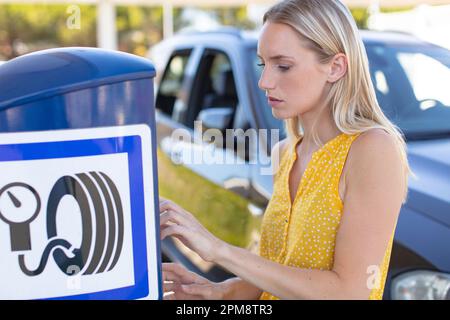 Frau, die den Reifendruck am Auto überprüft Stockfoto