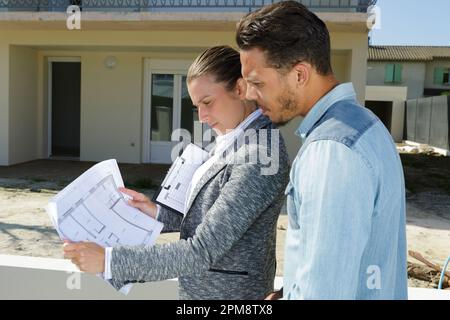 Mann und Frau beratende Grundrisse für Immobilien Stockfoto