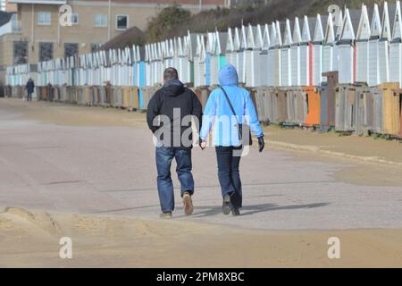 Storm Noa, Boscombe, Bournemouth, Dorset, Vereinigtes Königreich, 12. April 2023, Wetter. Ein Paar, das morgens bei starkem Wind und stürmischen Bedingungen am Meer an der Promenade entlang spaziert. Kredit: Paul Biggins/Alamy Live News Stockfoto