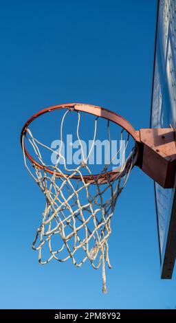 Basketballkorb von unten mit dem Mond im Netz und blauem Himmel. Stockfoto