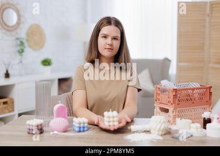 Handgefertigtes Konzept - Frau sitzt am Tisch und hält fertige Kerze in den Händen Stockfoto