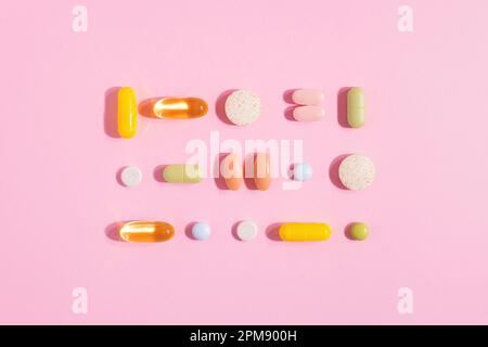 Medizinische Apotheke Pillen, Tabletten und Kapseln isoliert auf rosa Hintergrund. Knolling-Komposition, harte Schatten, Medizin und Gesundheitskonzept. Stockfoto