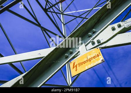 FOTOMONTAGE, Hochspannungsmast mit Schild und Aufschrift Strompreis, Symbolfoto Stromkosten Stockfoto