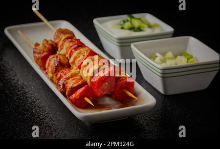 Würzige Hühnerkebabs auf Stöcken mit Salat. Stockfoto