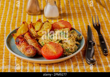 Wurst mit Pommes frites, Rührei und Tomaten. Stockfoto