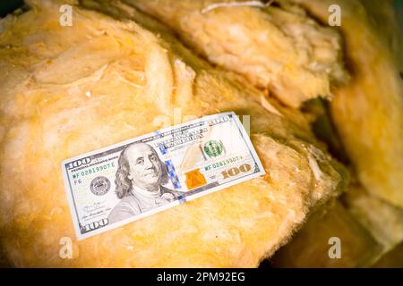 Hundert Dollar liegen auf Glaswolle Nahaufnahmen. Bargeld auf Baumaterialien für Dämmung und Schallisolierung. Steigende Preise für Baustoffe. Pur Stockfoto