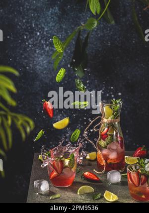 Cocktail mit Limette, zerstoßenem Eis, Erdbeeren und Minze mit fliegenden Zutaten auf dunklem Hintergrund, selektives Fokusbild, Text „Gewürz für Sie kopieren“, Su Stockfoto