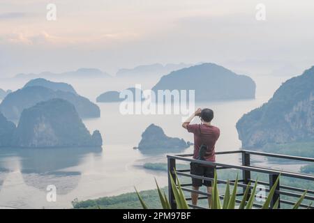 Ein Fotograf fotografiert einen wunderschönen Blick von der Samet Nanghse Aussichtsplattform in Thailand. Morgendlicher Blick auf die blauen Berge und Steine im Stockfoto
