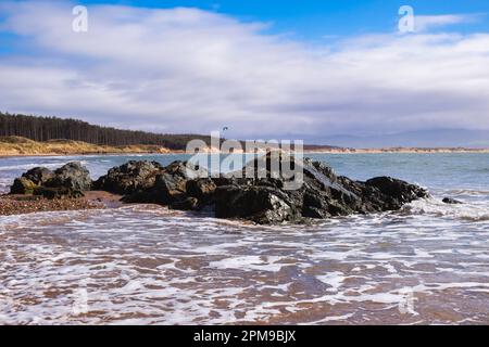Felsen und Meer bei Flut am Newborough Beach von Llanddwyn Island Ende Newborough, Isle of Anglesey, Wales, Vereinigtes Königreich, Großbritannien Stockfoto